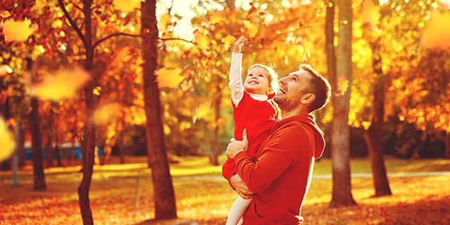 Father and child on a walk through park in autumn
