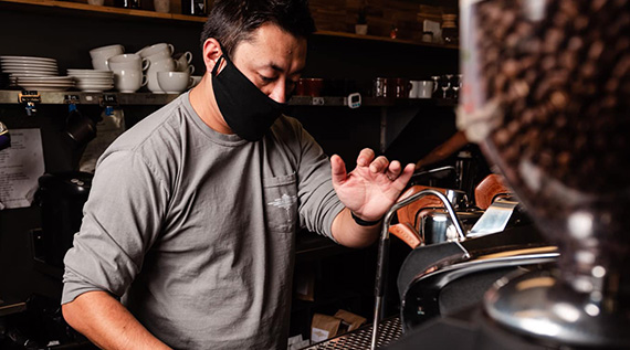 Man wearing mask, making coffee at Indaba