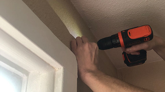 Closeup of a person's hands - using a drill to install a curtain rod