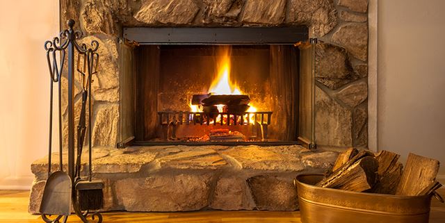 Stone fireplace with logs burning in a residential home