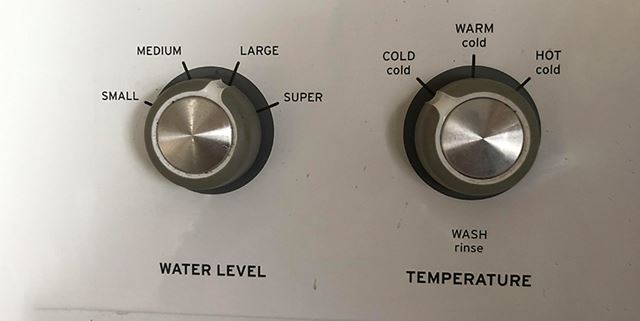 Closeup of knobs on a washing machine - The temperature knob has been turned to cold