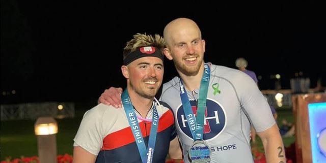 Two men posing and smiling with Ironman medals on