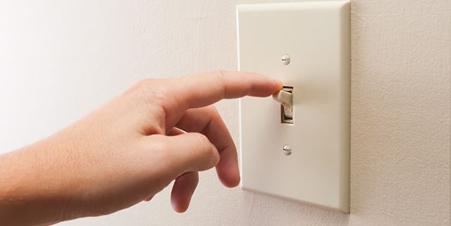 Closeup of a hand turning off a wall light switch