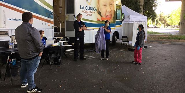 La Clinica traveling mobile health clinic parked with a few people outside