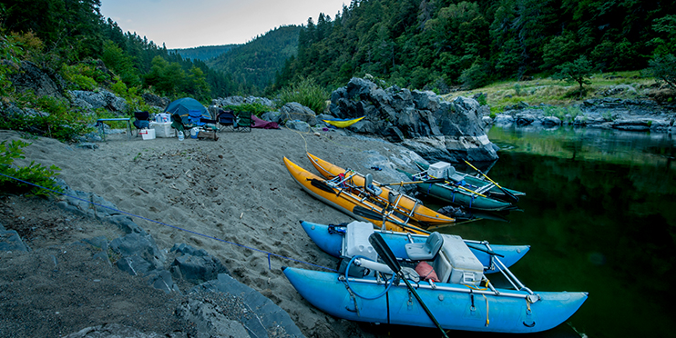 Camp near river with boats on the shore