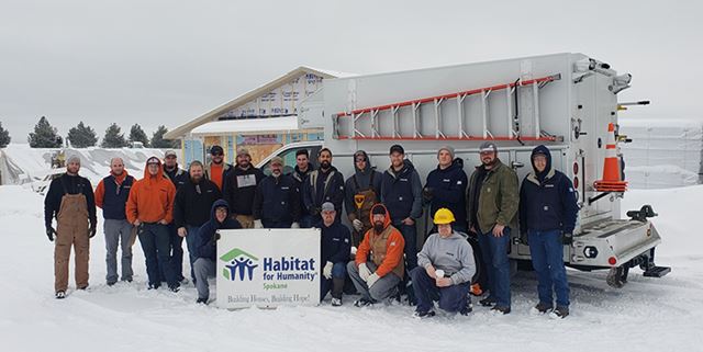 Avista employees posing with Habitat for Humanity sign in front of house