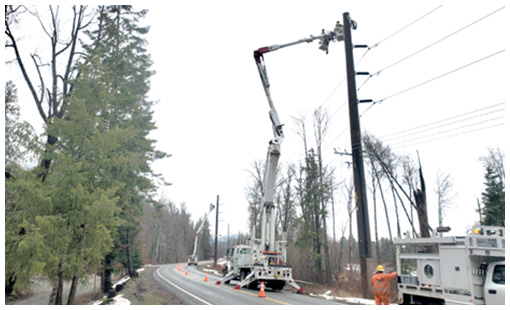 Avista trucks working to place transmission lines near the side of a road.