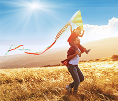 Son holding kite on father's shoulders