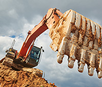 Large excavator on a pile of dirt outside.