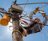 Lineman works on a power line on a sunny, blue sky day.