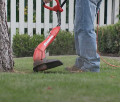 Man uses weed whacker outside in yard.