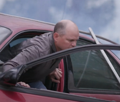 Man is preparing to leap out of his vehicle which has a power line fallen on top of it.